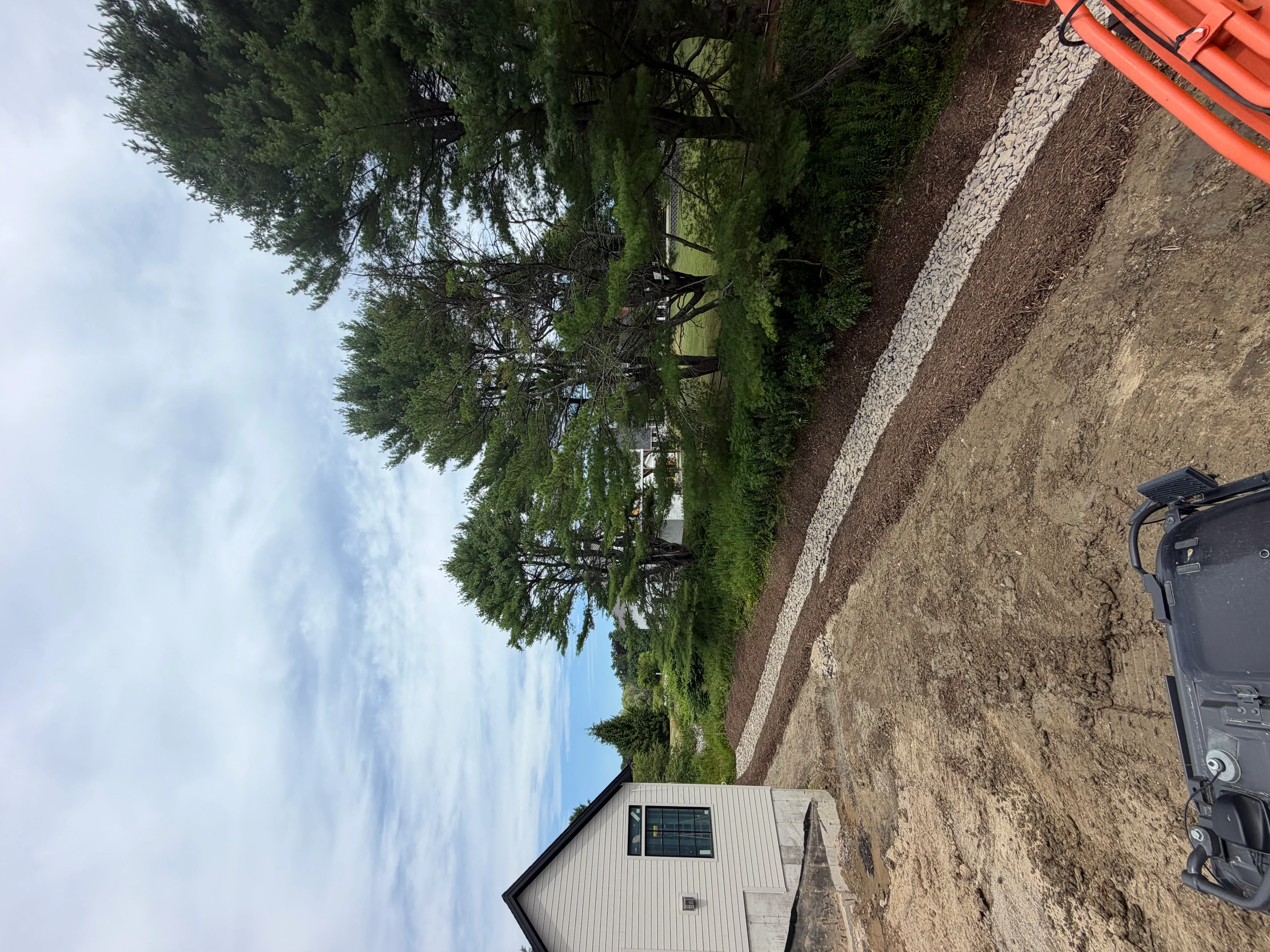 Graded gravel driveway with white stripe marking and cleared earthwork