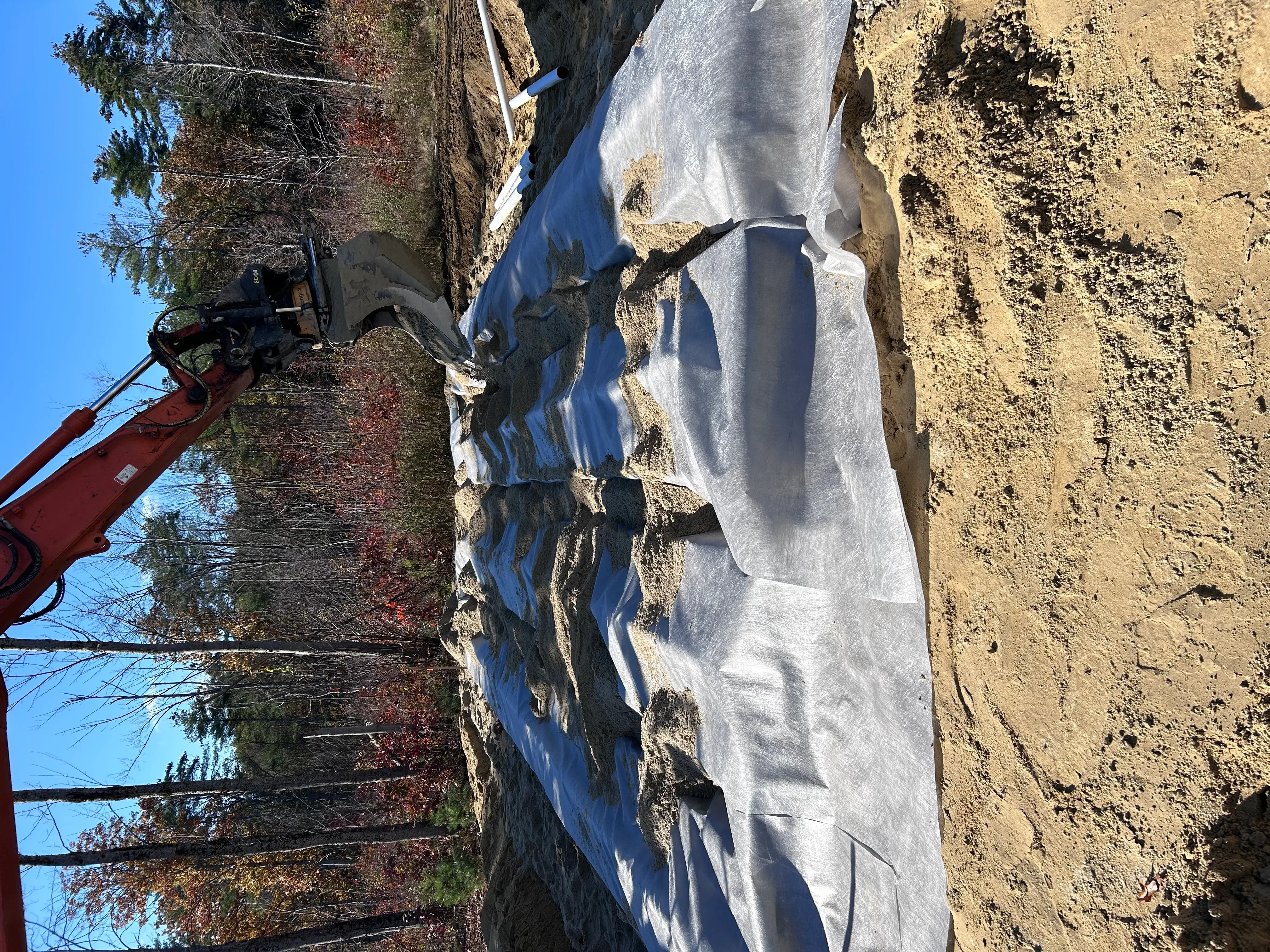 White erosion control fabric installed on sloped earthwork with equipment on site
