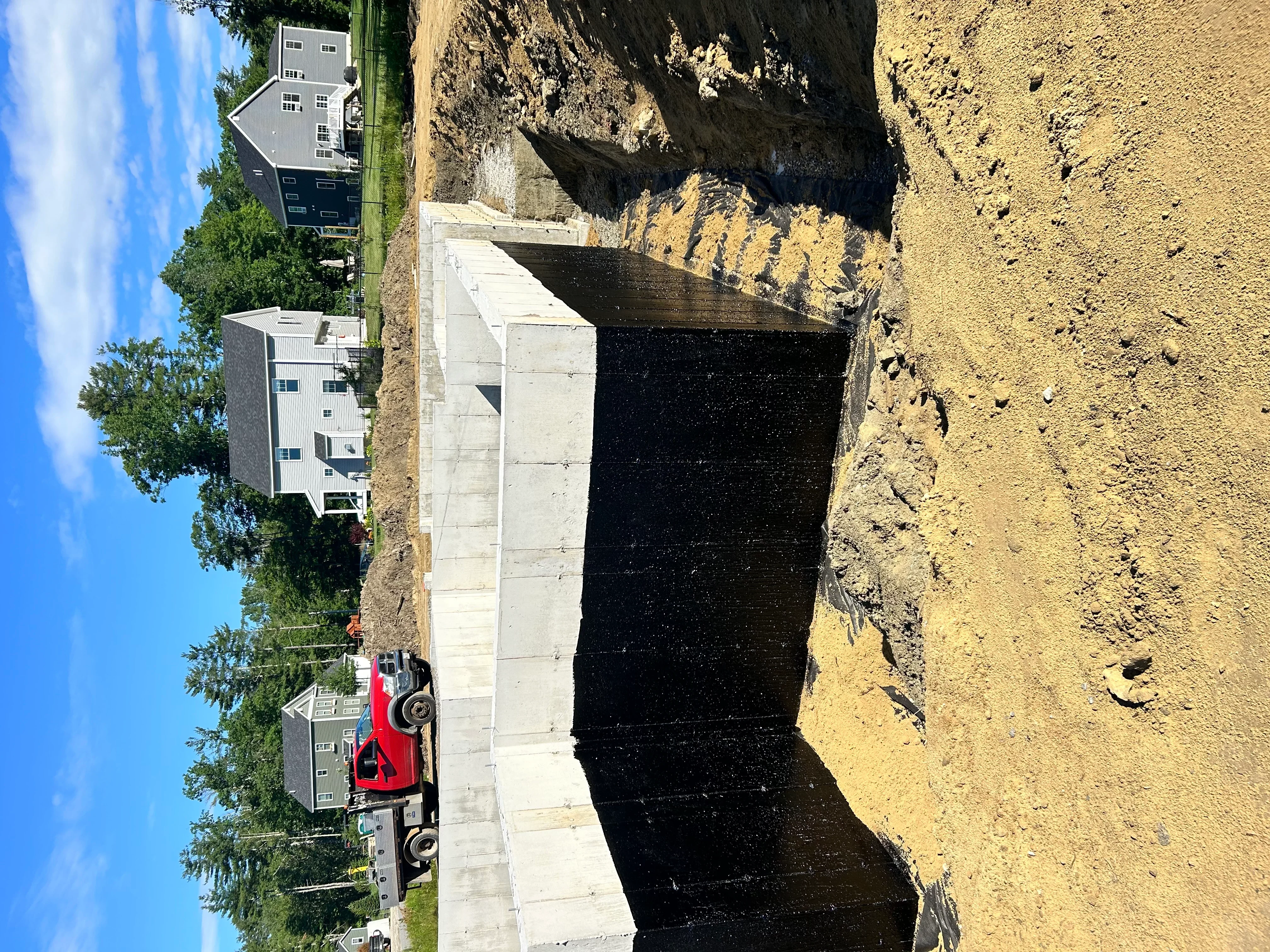 Excavation site with graded earth, concrete foundation, and heavy equipment during residential driveway construction