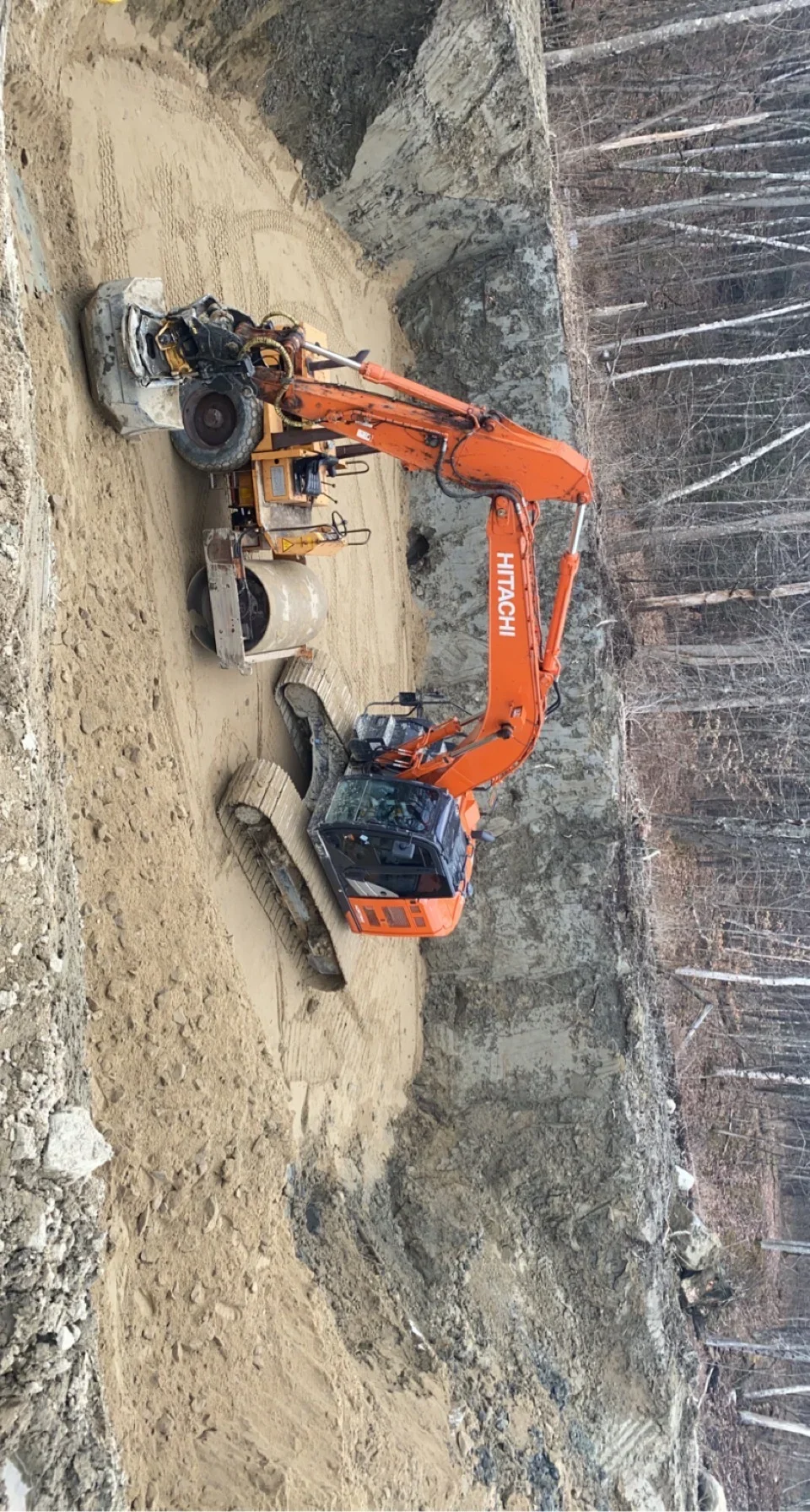 Mini excavator with compactor and support equipment on prepared soil site