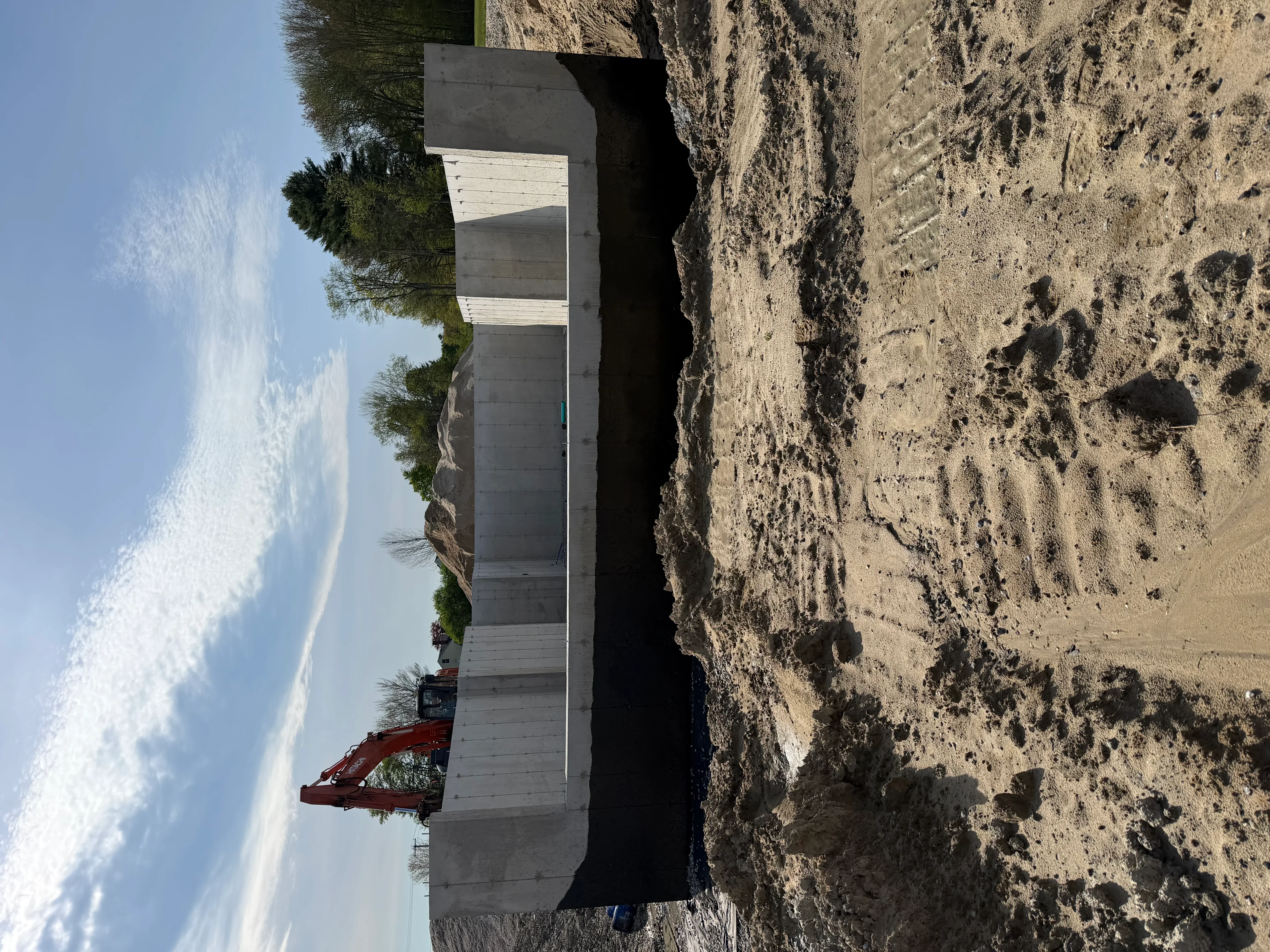 Concrete foundation structure with excavated earth and heavy equipment on construction site