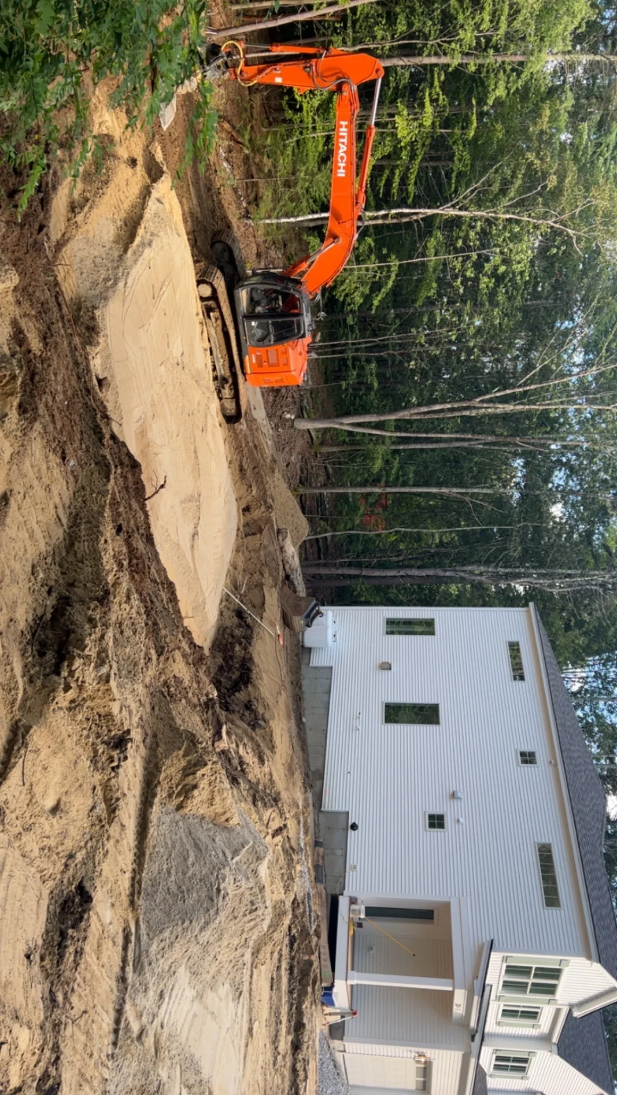 Orange excavator performing earth moving and site grading for residential construction