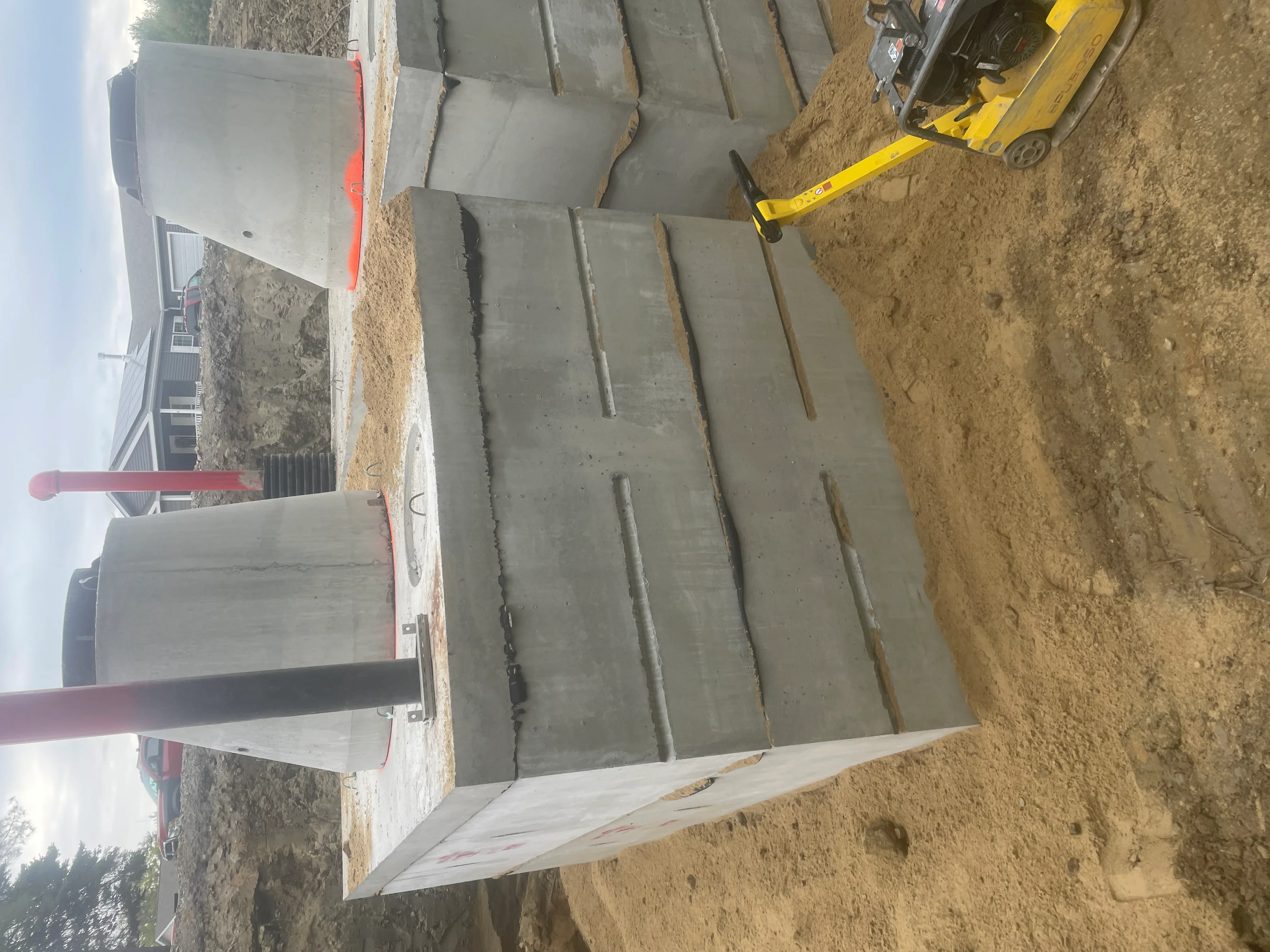 Concrete pad sections installed on compacted earth with construction equipment and site preparation