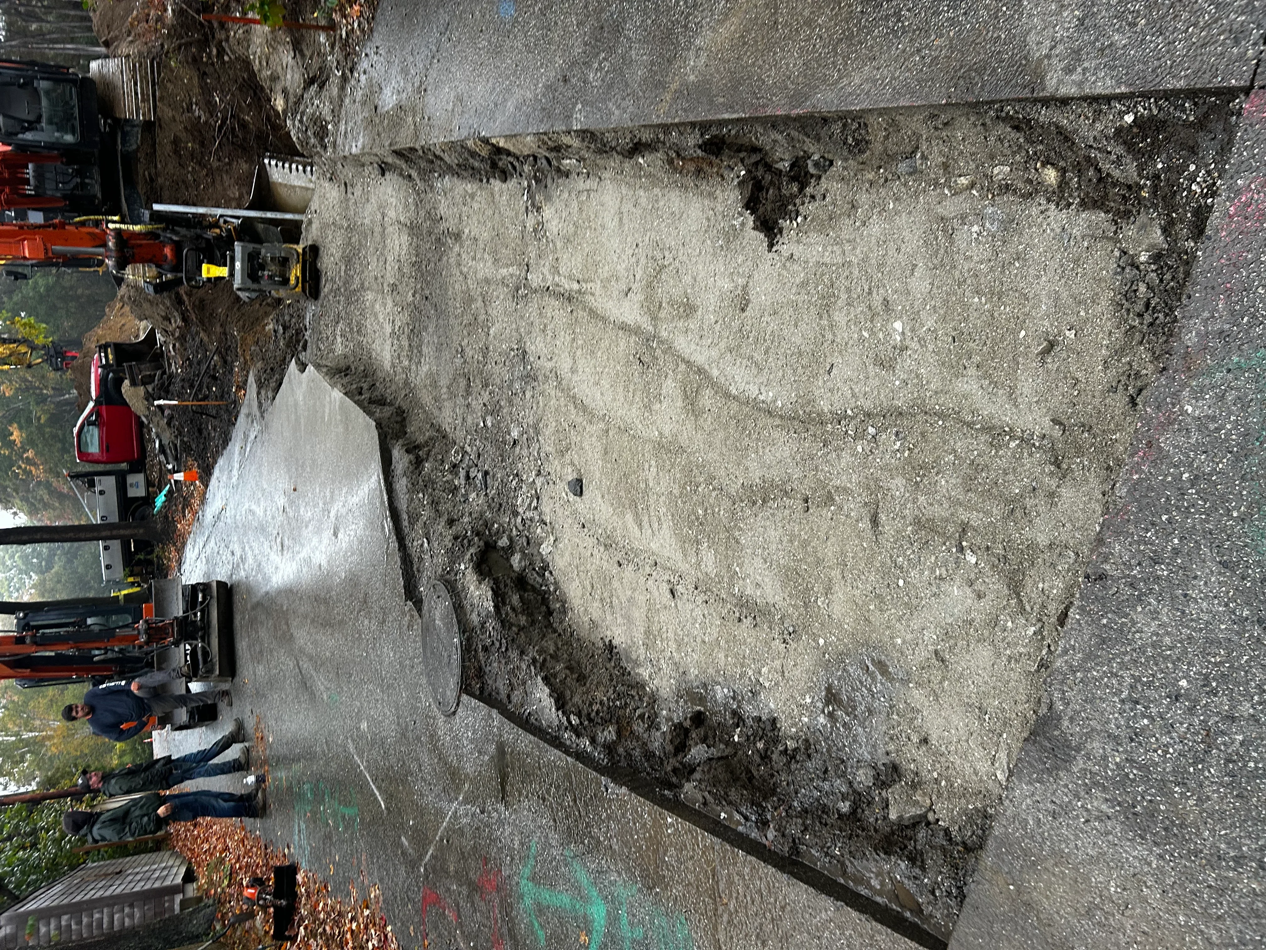 Excavator removing concrete pad debris with dump truck on active construction site