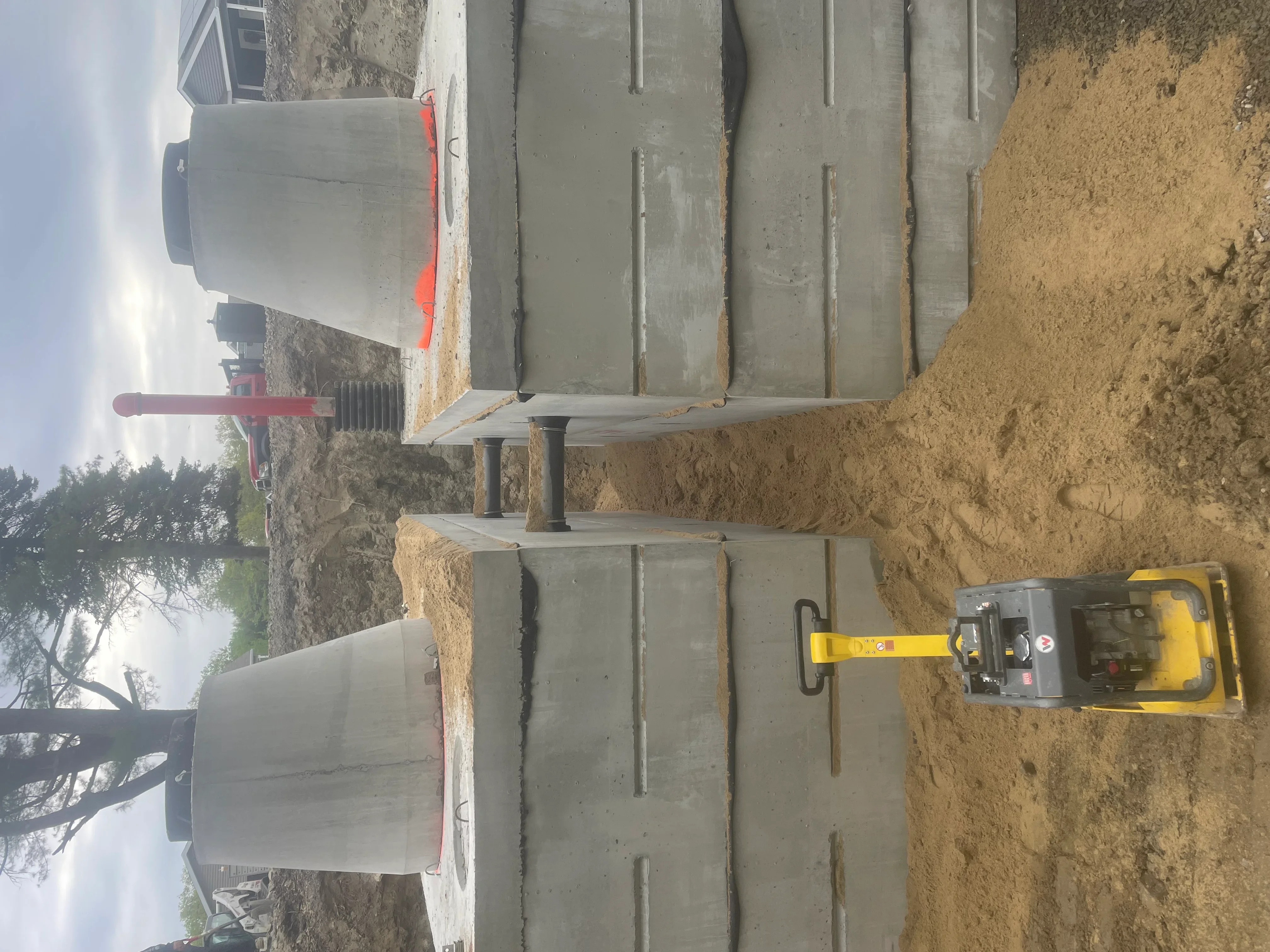 Concrete foundation footings with compacted soil base and plate compactor equipment on construction site