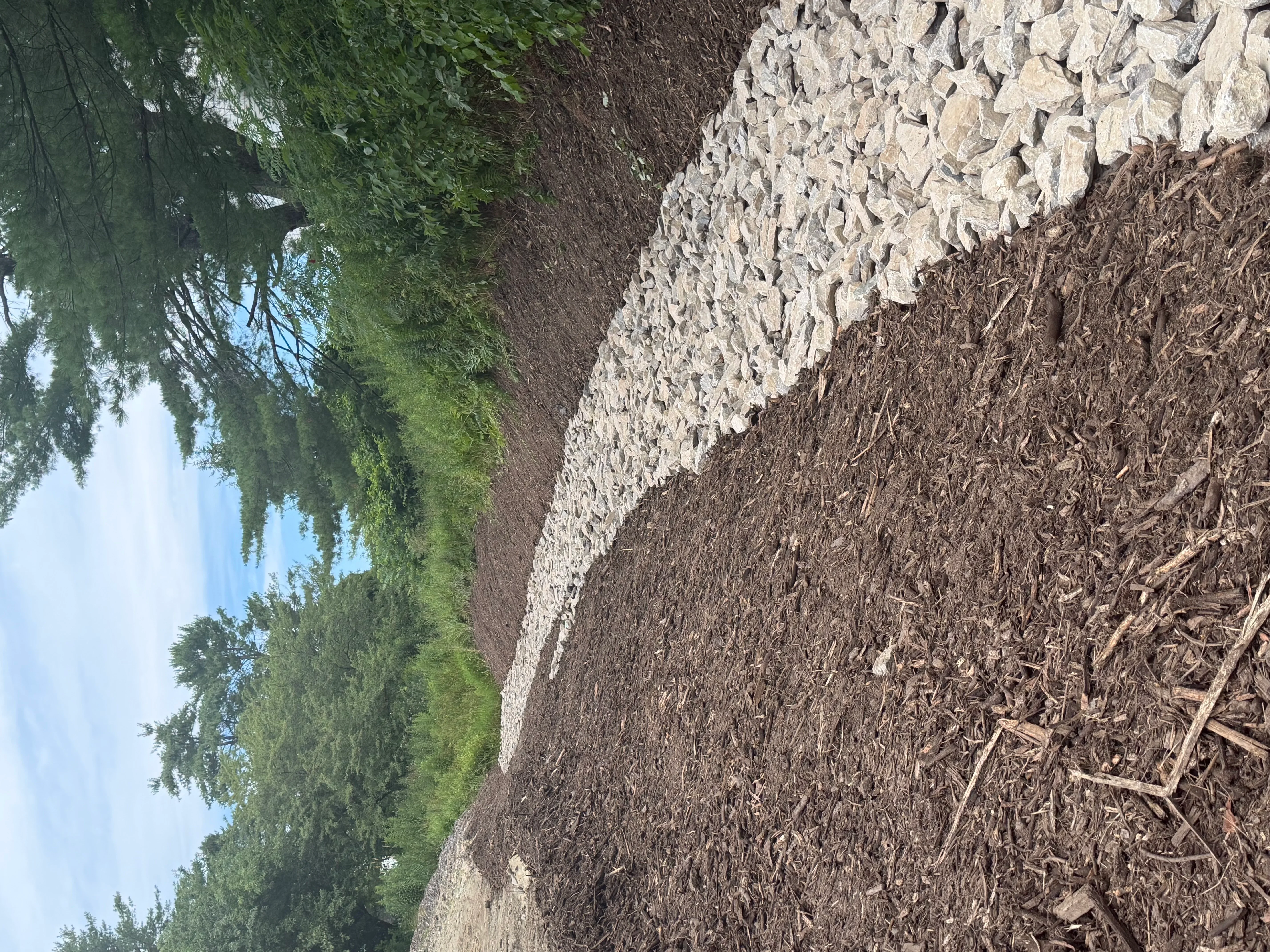 Crushed stone and mulch material spread on graded landscape with stone border edging