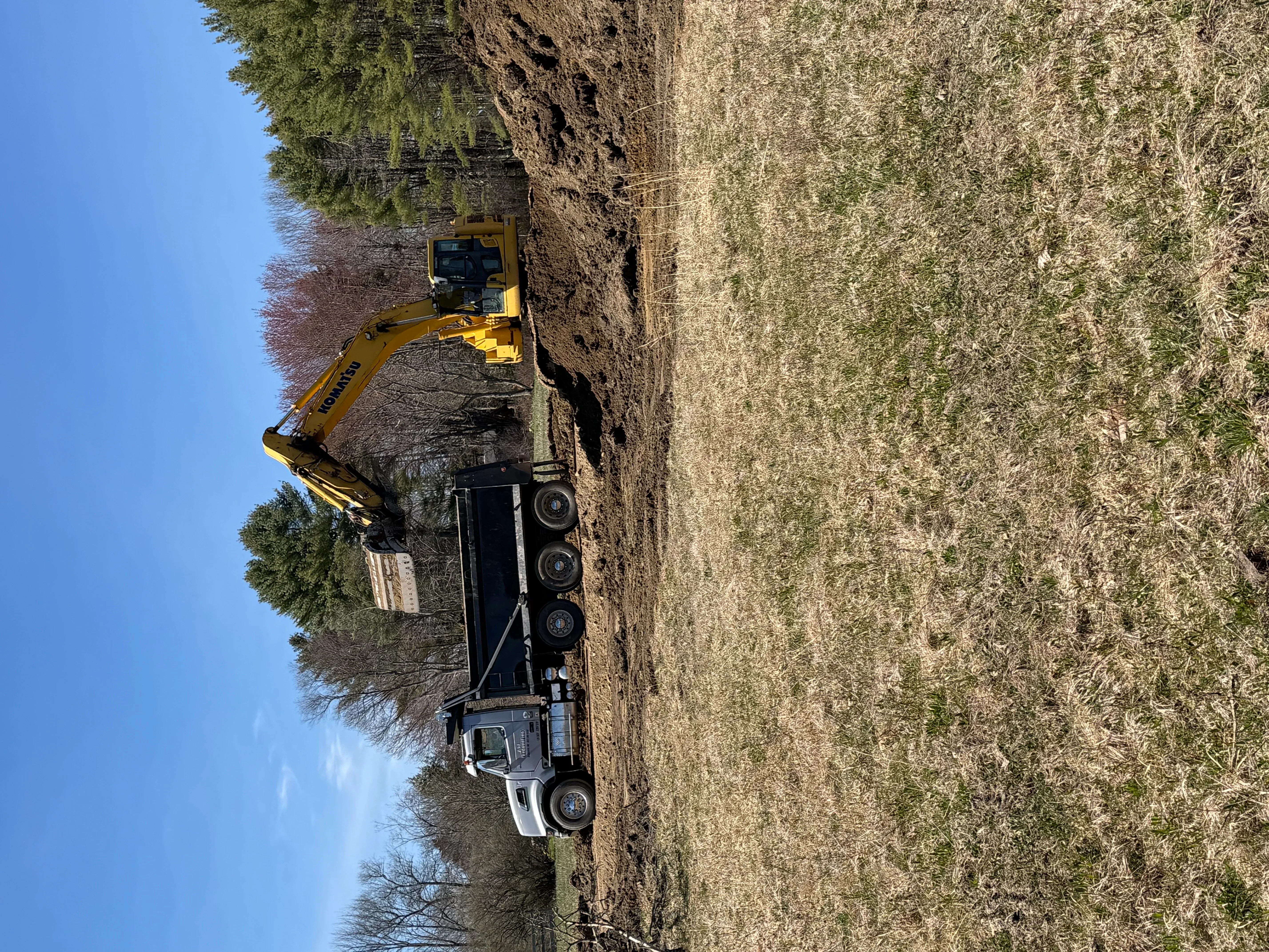 Yellow excavator loading dump truck with aggregate material on construction site