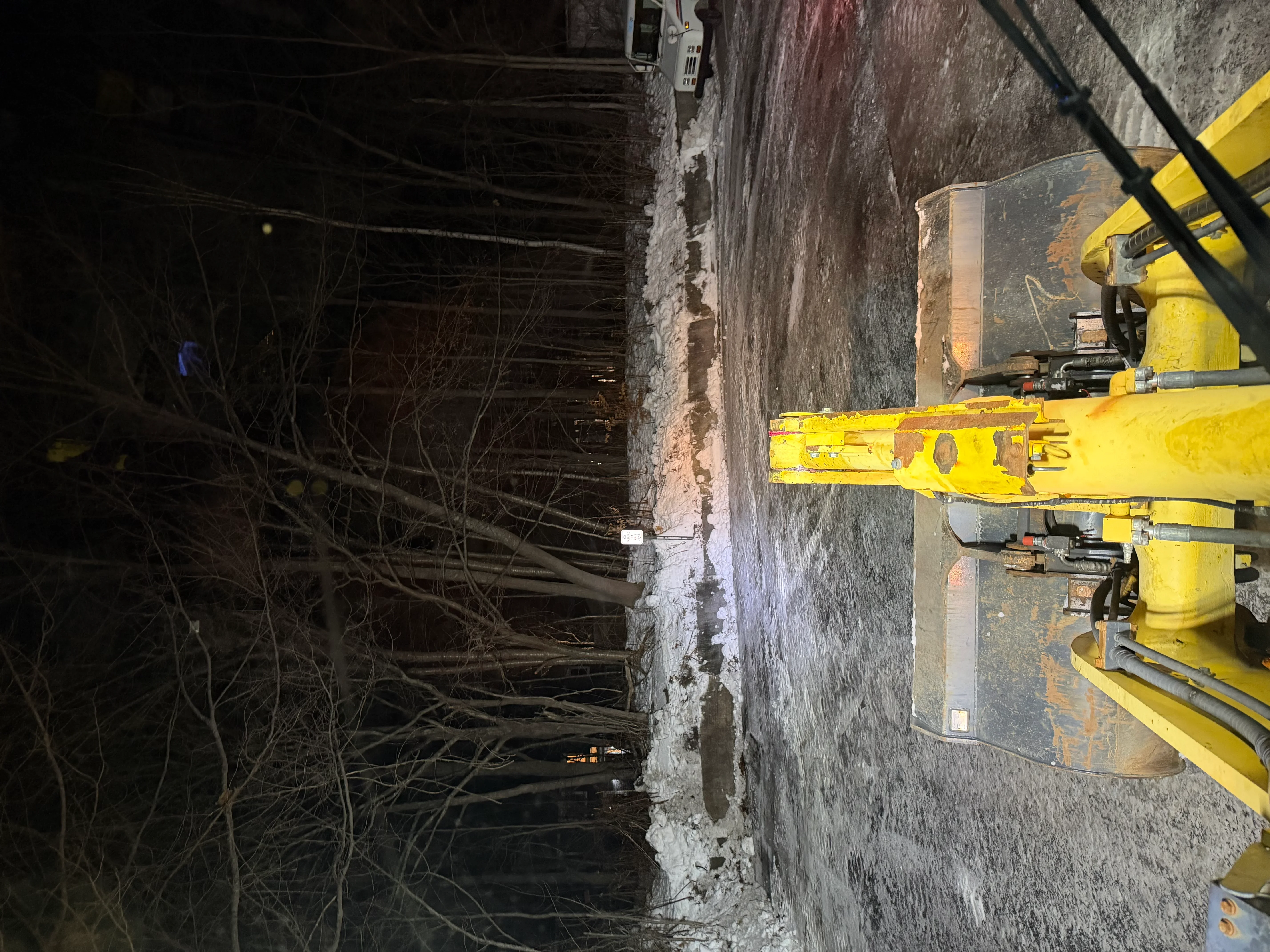 Yellow excavator removing concrete debris from industrial building interior