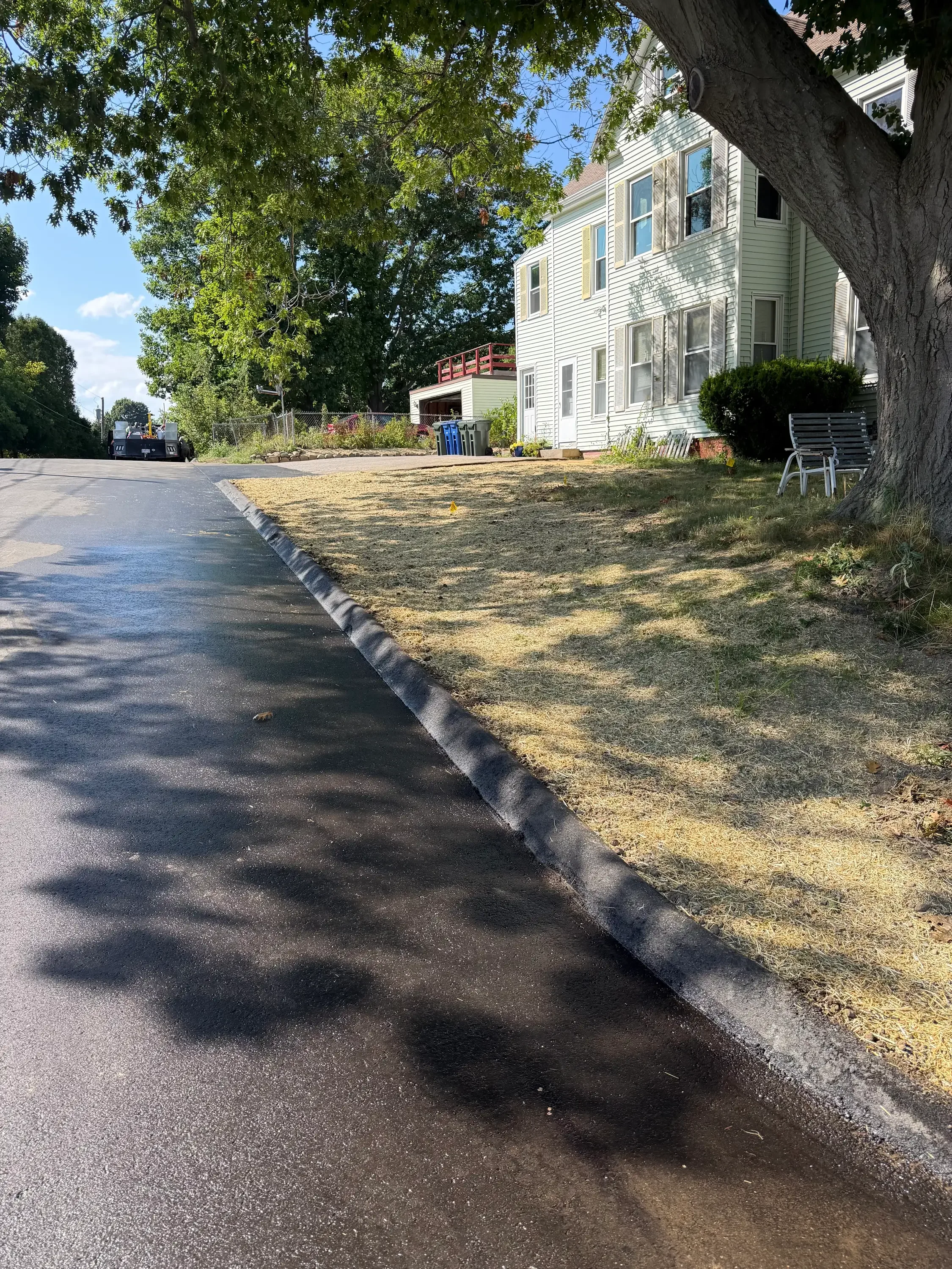 Newly graded residential lot with fresh asphalt driveway and concrete edging